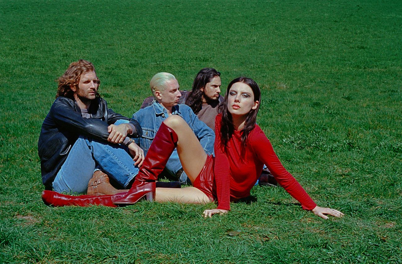 English alt-rock band Wolf Alice lounging on a grassy lawn in a promotional photo captured by photographer Rachel Fleminger Hudson.